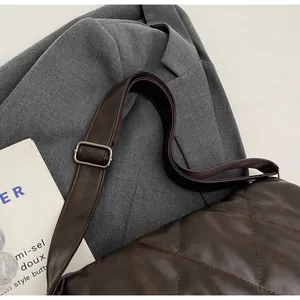 Détail du sac bandoulière matelassé marron avec large sangle réglable et boucle argentée
