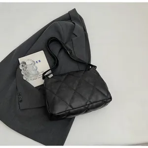 Détail d'un sac bandoulière matelassé noir avec texture en losanges au style minimaliste