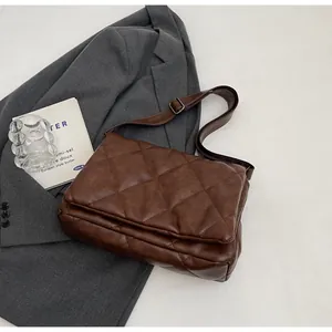 Gros plan d'un sac bandoulière marron matelassé avec bandoulière sur un blazer gris