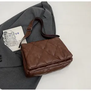Gros plan sur un sac bandoulière marron matelassé avec une large bandoulière réglable