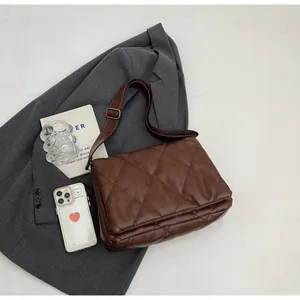 Sac bandoulière matelassé marron foncé sur blazer gris avec accessoires déco