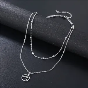 Double-layered silver necklace with wave pendant and metallic beads on a black background