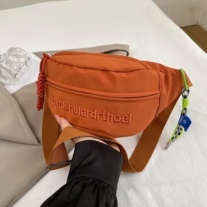 Detail der orangefarbenen Segeltuch-Brusttasche mit Stickerei und grünem geflochtenem Seil