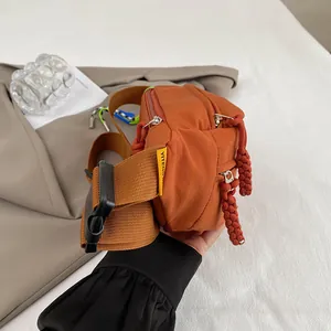 Detailansicht der orangefarbenen Nylon-Brusttasche mit breitem Gurt und Steckschnalle