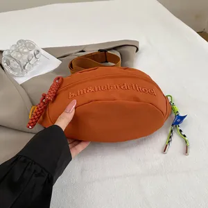 Detail der orangen Segeltuch-Brusttasche mit Stickerei und gewebtem Reißverschluss