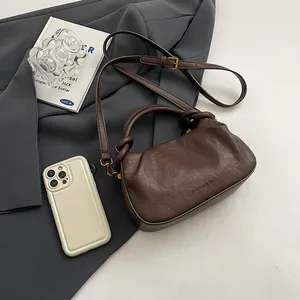 Close-up of dark coffee pleated cloud bag with knotted handle and fine leather texture