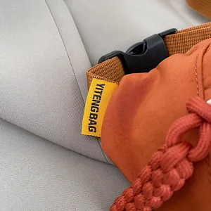 Nahaufnahme der orangefarbenen Brusttasche mit Stofftextur und Kunststoffschnalle