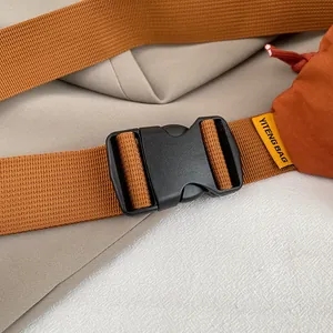Nahaufnahme der schwarzen Kunststoffschnalle und orangefarbenem Nylonband mit Markenetikett