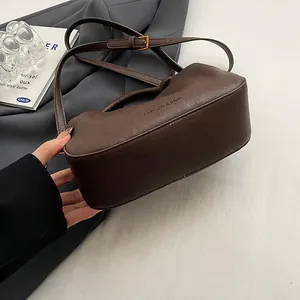 Detailed shot of dark brown pleated cloud bag with gold buckle and adjustable strap