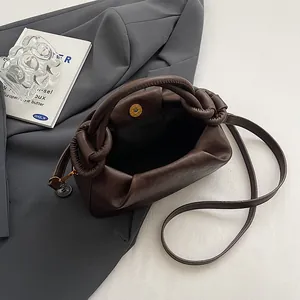 Detail of dark brown pleated cloud bag featuring knotted handle and magnetic metal closure