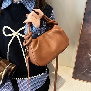 Detail of a brown pleated cloud bag showing the side knot design and adjustable strap
