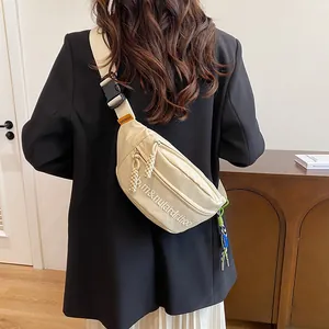 Detailansicht der beigen Canvas-Brusttasche mit Stickerei und Logo-Etiketten am Gurt
