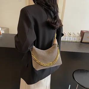 Détail du sac bandoulière en daim gris avec chaîne dorée épaisse sur modèle féminin