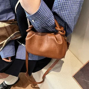 Detail showing brown pleated cloud bag texture with adjustable strap and knot handle