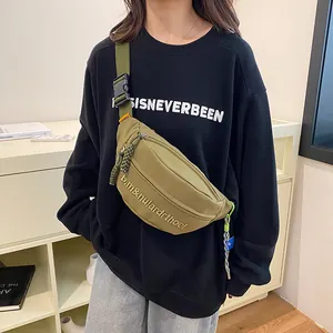 Olivgrüne Canvas-Brusttasche mit verstellbarem Gurt, getragen von Model auf schwarzem Hoodie