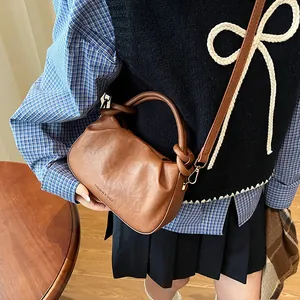 Close-up of deep brown pleated cloud bag featuring a unique knotted handle and logo