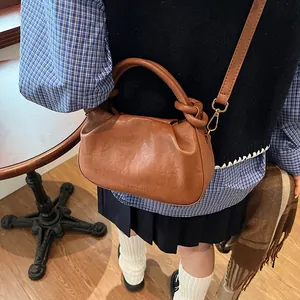 Detail of vintage brown leather bag featuring unique knotted handle and pleated texture