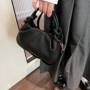 Detail of black pleated cloud bag featuring golden ring buckle and soft leather texture