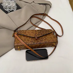 Dettaglio della borsa a tracolla leopardata con fibbie dorate vicino a uno smartphone