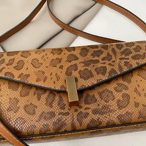 Dettaglio borsa baguette leopardata con trama a serpente e chiusura in metallo dorato