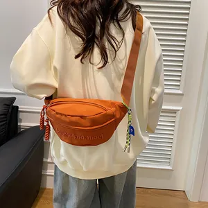 Detail der leuchtend orangen Brusttasche aus Canvas mit Reißverschluss am Model