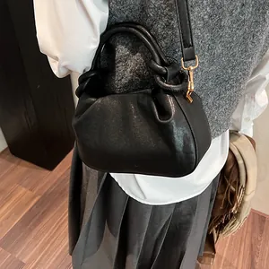Detailed view of black pleated cloud bag carried as a handbag with textured leather finish