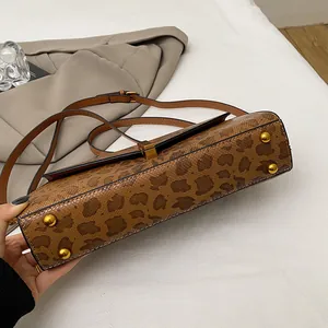 Dettaglio borsa leopardata con borchie protettive dorate e trama in pelle di serpente