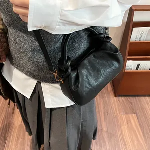 Detail of black pleated cloud bag with textured leather and gold metal hardware