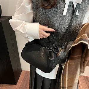 Detail of black pleated cloud bag with a top handle and slim detachable shoulder strap