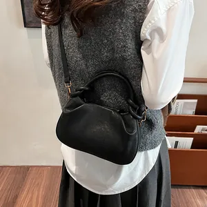 Sac boulette noir mat avec poignée torsadée sur mannequin pour un look décontracté