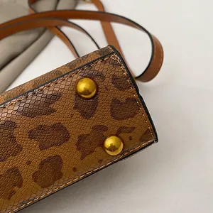 Dettaglio della trama leopardata marrone e borchie dorate sul fondo della borsa