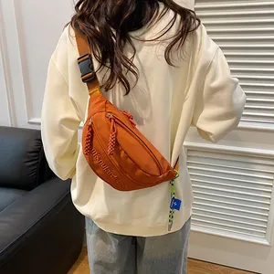 Nahaufnahme der orangefarbenen Nylon-Brusttasche mit Stickerei und verstellbarem Schultergurt