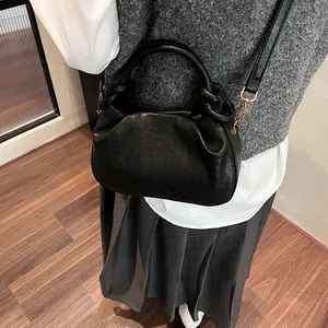 Detail shot of a black pleated cloud bag featuring matte leather and a gold hook