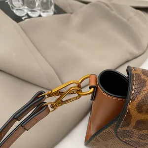Dettaglio ravvicinato del tessuto leopardato con pelle marrone e fibbie in ottone