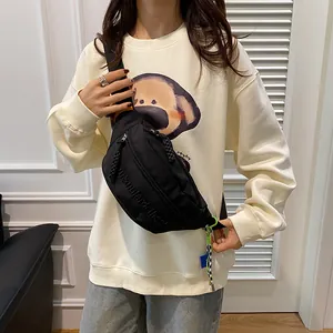 Nahaufnahme der schwarzen Crossbody-Brusttasche mit Reliefbuchstaben und Reißverschlüssen
