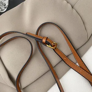 Dettaglio tracolla in pelle marrone con fibbia dorata e cuciture bianche per borsa retrò