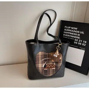 Detail der Ledertasche mit Herz-Karof Herz-Karo-Patch, Hunde-Stickerei und Plüsch-Löwen-Anhänger