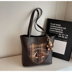 Detailansicht der braunen Ledertasche mit Dackel-Stickerei und Herz-Karomuster-Patchwork
