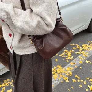 Close-up of brown pleated cloud bag with leather texture and embossed fashion text details