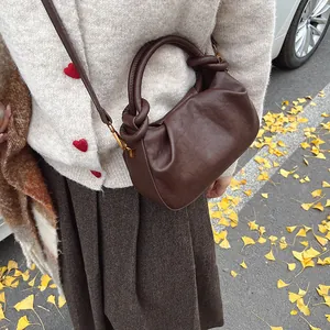 Detail of dark brown pleated cloud bag featuring soft leather texture and golden hardware