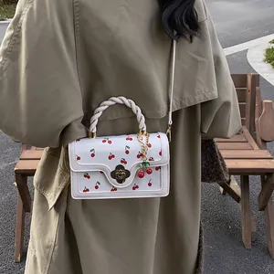 Dettaglio della borsa bianca con stampa ciliegie e chiusura a petalo in metallo dorato