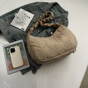 Detail of beige quilted hobo bag featuring wavy stitching and a unique pleated strap