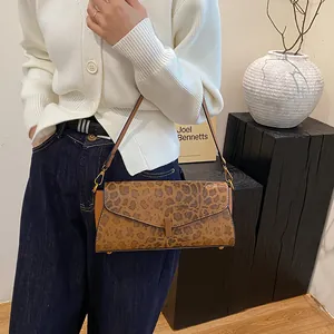 Dettaglio borsa baguette leopardata con chiusura a rotazione dorata e tracolla sottile