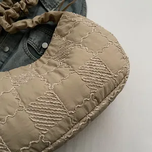 Detail of khaki quilted puffer bag featuring wave embroidery and scrunchie strap