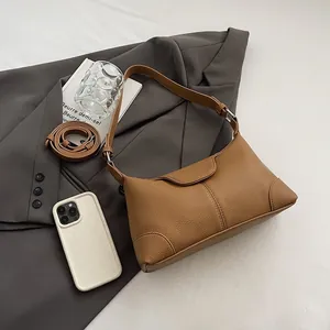 Détail du sac hobo caramel grainé posé sur un blazer gris avec des magazines de mode chic