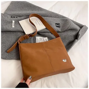 Close-up of brown tote bag featuring matte leather texture and silver heart buckle detail