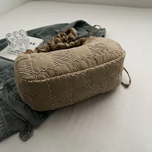 Detail of khaki quilted handbag with cloud-like gathered handle and embroidered texture