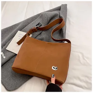 Detailed close-up of brown matte leather shoulder bag with vertical stitching and silver bead