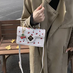Foto lifestyle di una borsa a tracolla bianca con stampa ciliegia e chiusura a fiore