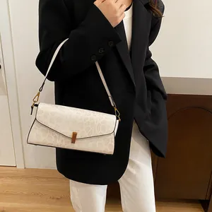 Dettaglio borsa baguette beige motivo serpente con fibbia dorata indossata dalla modella